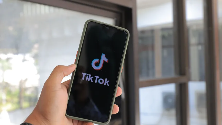 A person holding a phone displaying the TikTok app.